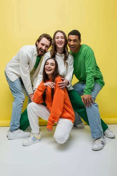 Amigos multiétnicos positivos posando no fundo amarelo — Fotografia de Stock