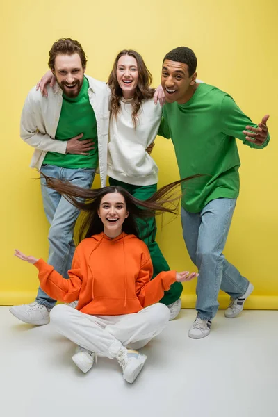 Multiethnic friends looking at camera on yellow background — Stock Photo