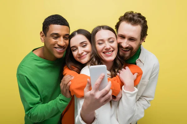 Positivo interrazziale amici prendendo selfie su smartphone isolato su giallo — Foto stock
