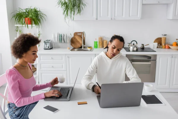 African american freelancers using laptops in kitchen — Stock Photo