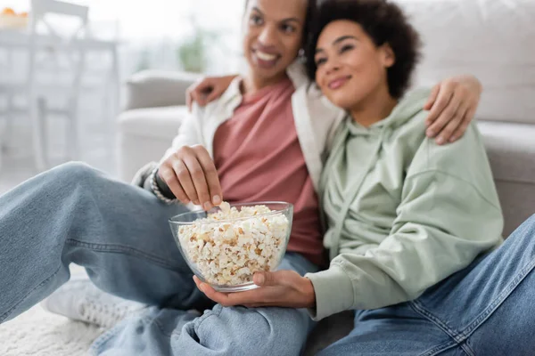 Blurred african american couple with popcorn hugging at home — Stock Photo