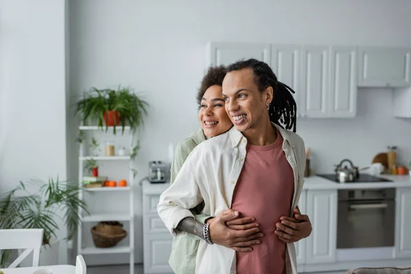 African american woman hugging tattooed boyfriend at home — Stock Photo