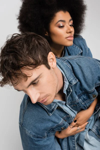 Young man looking away near african american woman on blurred background isolated on grey — Stock Photo