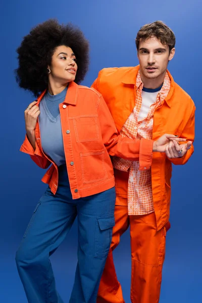 Stylish man holding hand of smiling african american woman isolated on blue — Stock Photo