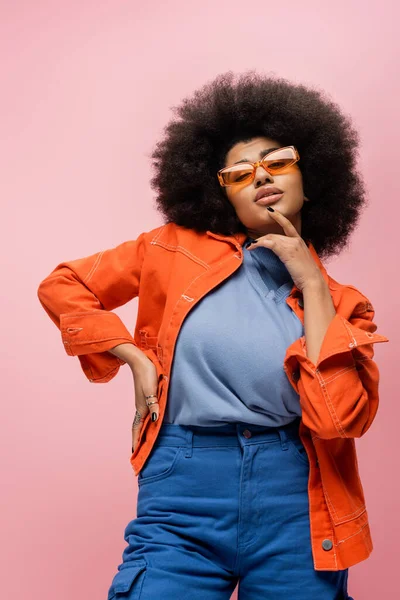 Portrait of trendy african american woman in sunglasses looking at camera isolated on pink — Stock Photo