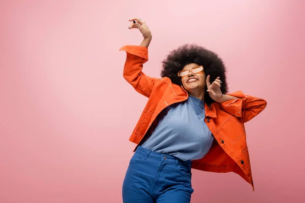 Cheerful african american model in sunglasses and orange jacket isolated on pink - foto de stock