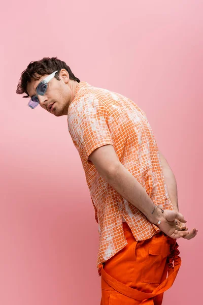 Trendy man in sunglasses looking at camera isolated on pink — Stock Photo