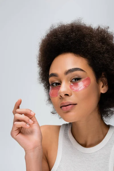 Young african american woman with collagen eye patches looking at camera isolated on grey — Stock Photo