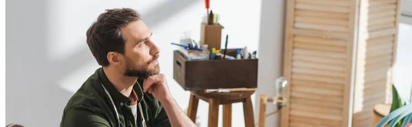 Pensive carpenter looking away in blurred workshop, banner — Foto stock