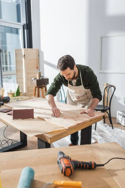 Craftsman using sandpaper on wooden board in workshop — Stock Photo