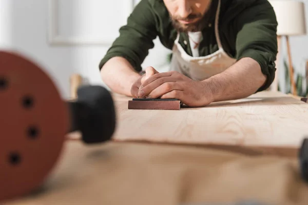 Cropped view of blurred restorer sanding wood in workshop — Stock Photo