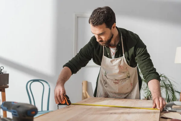 Brunette restaurateur mesurant panneau en bois sur la table — Photo de stock