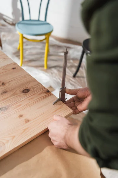 Cropped view of restorer measuring wooden board with calipers in workshop — Foto stock