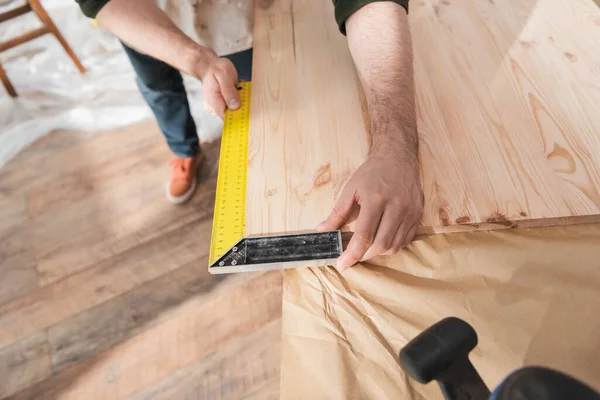 Vista cortada de carpinteiro usando ferramenta quadrada na placa de madeira — Fotografia de Stock