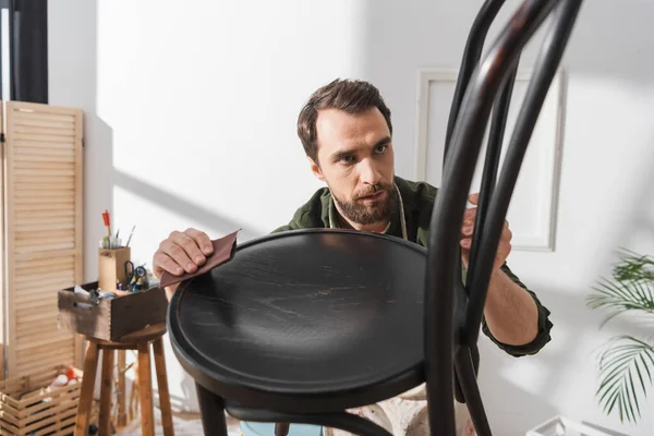 Focused restorer sanding wooden chair in workshop — Stock Photo