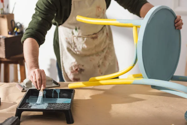 Cropped view of restorer repainting wooden chair on table — Stock Photo