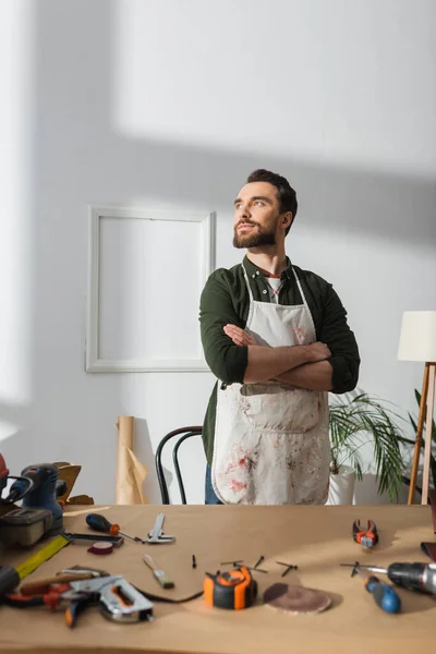 Confident restorer looking away while standing near tools in workshop — Foto stock