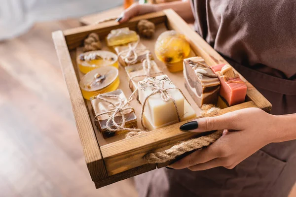 Wooden tray with assortment of handmade soap in hands of cropped african american craftswoman — Stockfoto