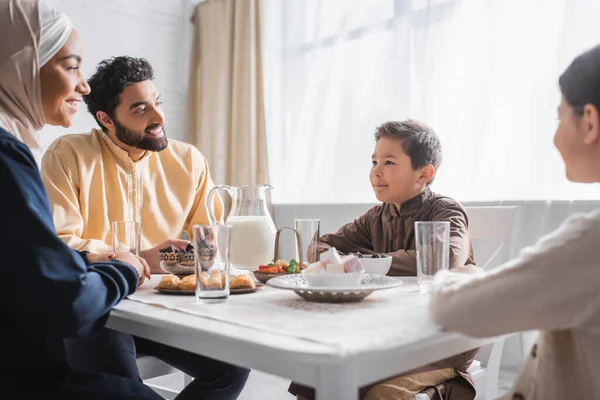Sorridente famiglia musulmana guardando ragazzo vicino al cibo durante il ramadan — Foto stock