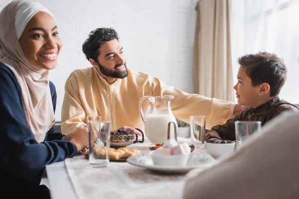 Muslim father looking at son near family during suhur in morning at home — Stock Photo