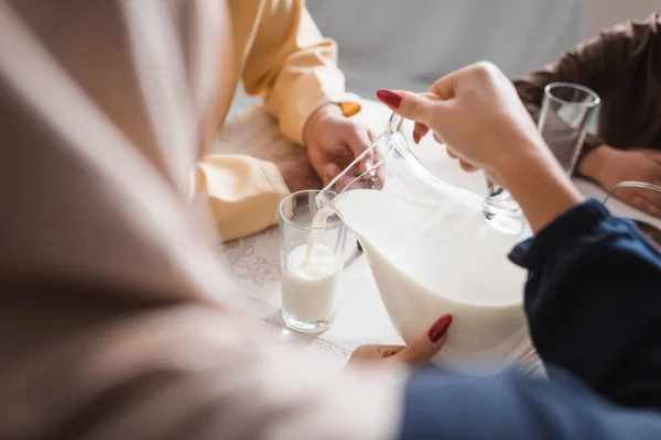 Arabian woman pouring milk during suhur with family in morning at home — Foto stock