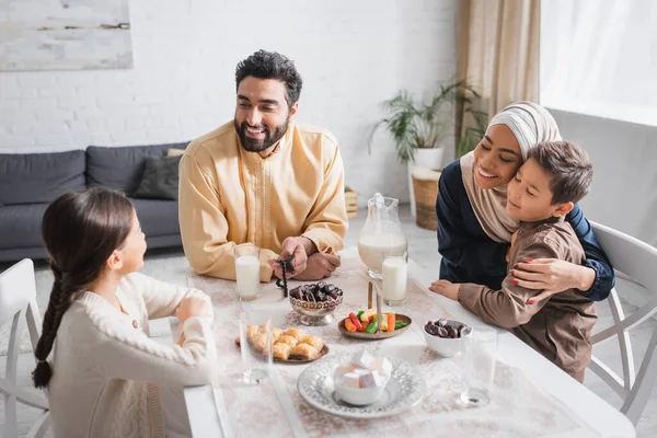 Positive muslim family sitting near food during suhur in morning at home — Foto stock