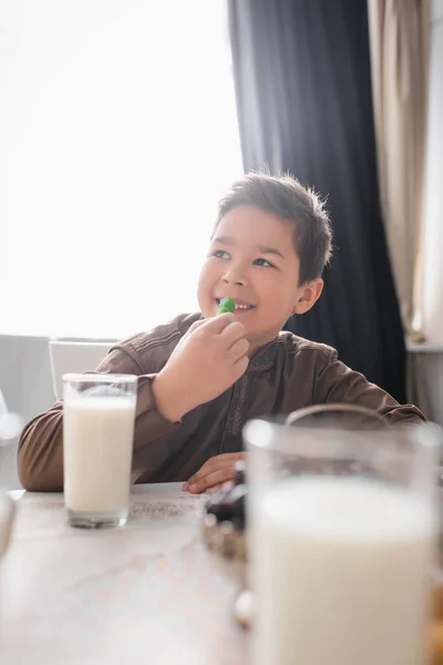 Smiling muslim kid holding cevizli sucuk near ramadan breakfast at home — Stock Photo