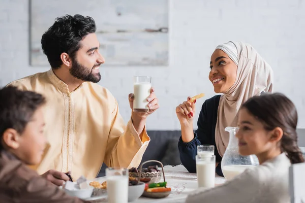 Genitori musulmani felici che si guardano a vicenda vicino a bambini offuscati e suhur colazione a casa — Foto stock