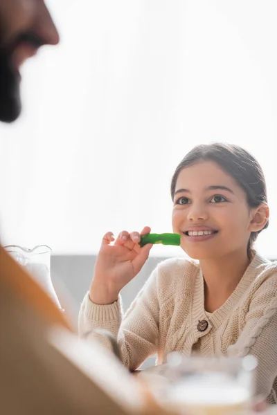 Smiling muslim girl holding cevizli sucuk near blurred father at home — Stock Photo