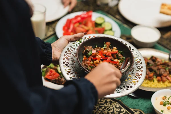 Cropped view of muslim woman holding delicious meal during ramadan at home — Foto stock