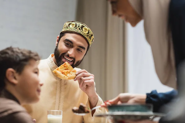 Щасливий мусульманський батько тримає питу хліб біля розмитої сім'ї вдома — стокове фото