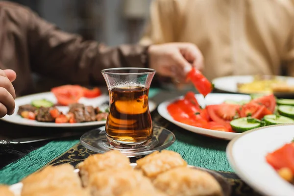 Turkish tea glass near food and muslim boy during ramadan dinner - foto de stock