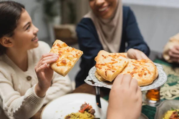 Muslim mother holding pita bread near children and ramadan dinner - foto de stock