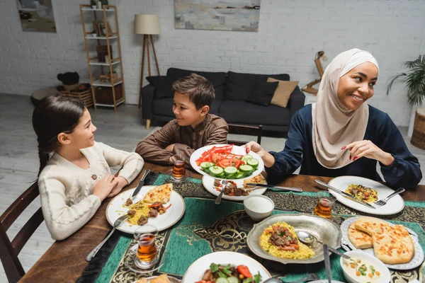 African american mother holding vegetables near kids during ramadan at home — Stockfoto