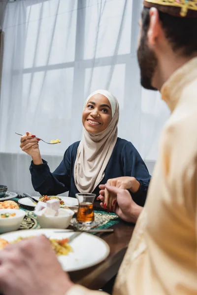 Afro-americano mulher no hijab segurando mão de desfocado marido perto ramadã jantar em casa — Fotografia de Stock