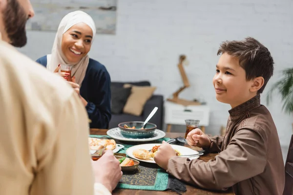 Muslim parents looking at son near tasty dinner at home — Stock Photo