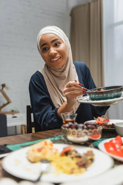 Sorrindo afro-americana em hijab segurando comida durante iftar em casa — Fotografia de Stock