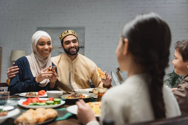 Lächelnde muslimische Eltern umarmen ihre Kinder beim Iftar zu Hause — Stockfoto