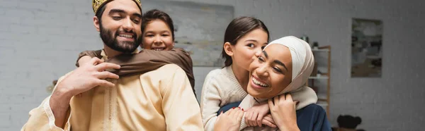 Familia positiva del Medio Oriente con niños abrazándose en casa, pancarta - foto de stock