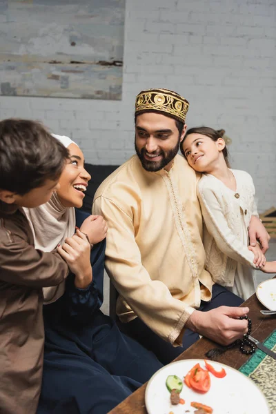 Smiling arabian man hugging daughter and looking at family during ramadan at home — Stockfoto