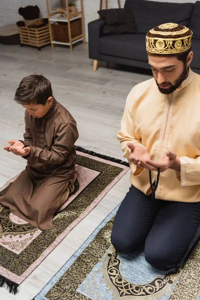 Muslim father with prayer beads praying near son at home — Stock Photo