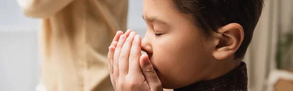 Muslim child praying near blurred parent during salah at home, banner — Stock Photo