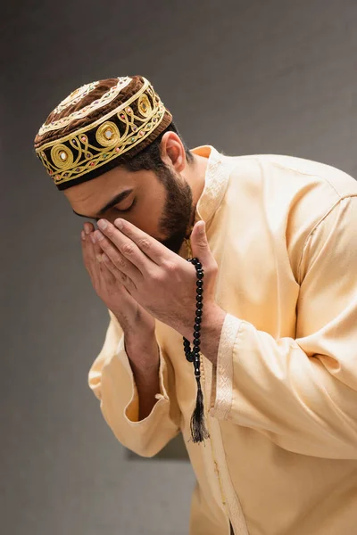 Young muslim man with prayer beads doing salah at home — Stock Photo