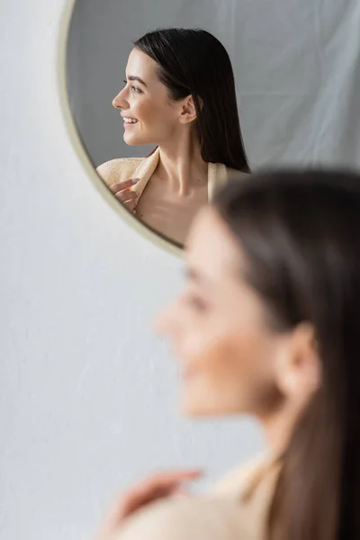 Reflexão de sorrir jovem mulher olhando para longe no espelho do banheiro — Fotografia de Stock
