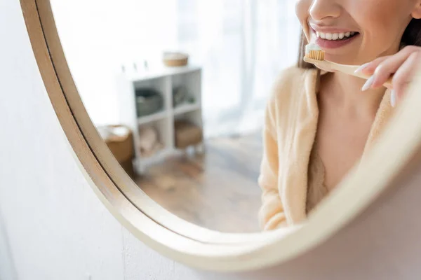 Обрізаний вид на молоду і веселу жінку чистить зуби біля дзеркала у ванній — стокове фото
