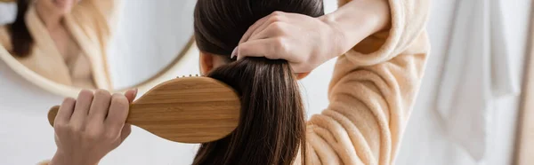 Rückseite junge brünette Frau beim Haareputzen im Badezimmer, Banner — Stockfoto