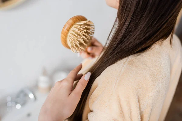 Обрізаний вид молодої жінки чистить блискуче волосся у ванній — стокове фото