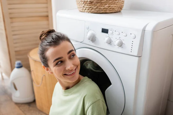 Lächelnde Frau schaut zu Hause auf Waschmaschine — Stockfoto