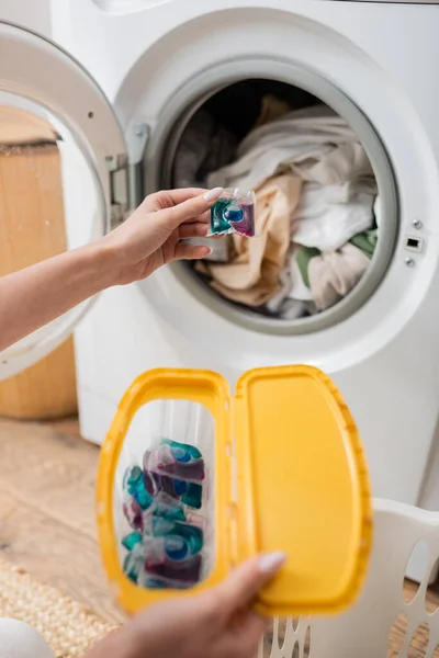 Ausgeschnittene Ansicht einer Frau, die Waschmittel in der Nähe der Waschmaschine in der Waschküche hält — Stockfoto