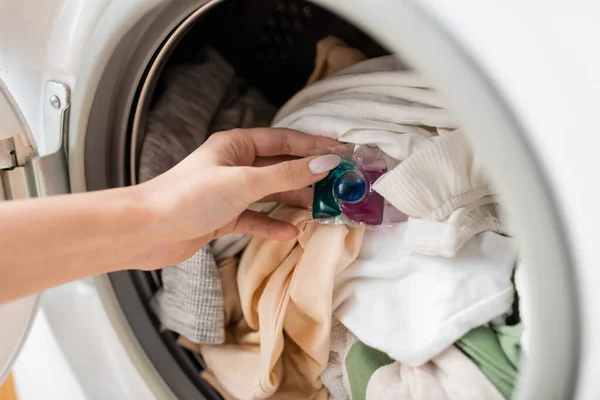 Cropped view of woman putting detergent pod on clothes in washing machine — Stockfoto